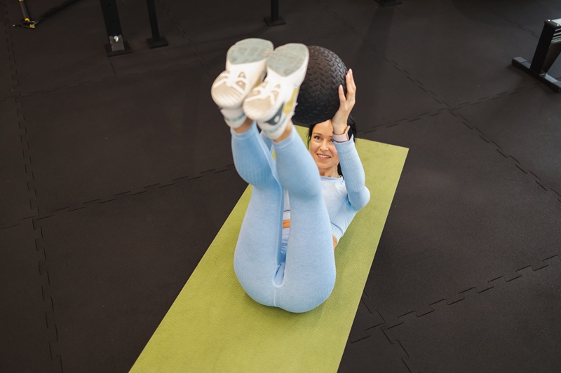 A woman doing mobility exercises with a medicine ball.